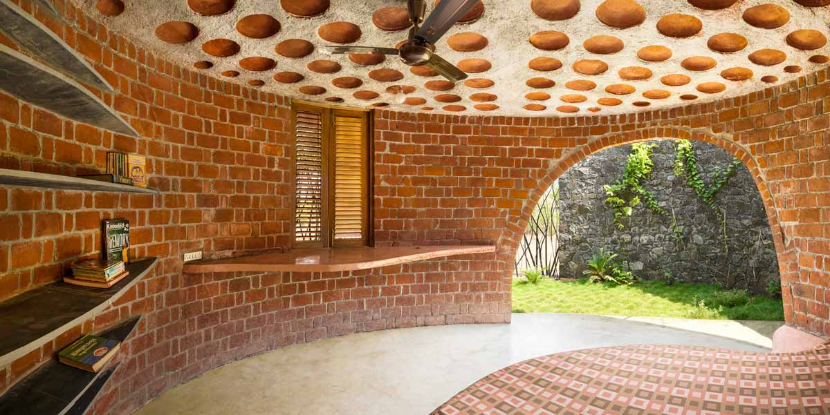 The interior of a circular brick room showcases cultural heritage, with a patterned ceiling.