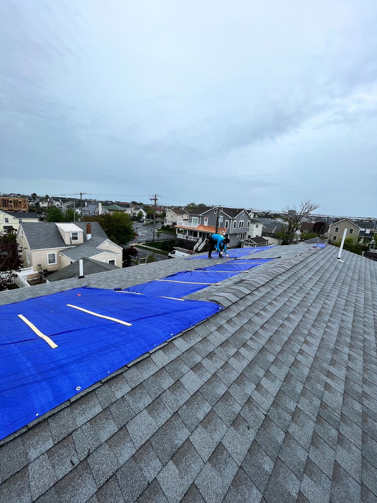 Roof leak repair near me in progress, with a tarp covering damaged shingles to protect against further water intrusion until permanent repairs can be made.