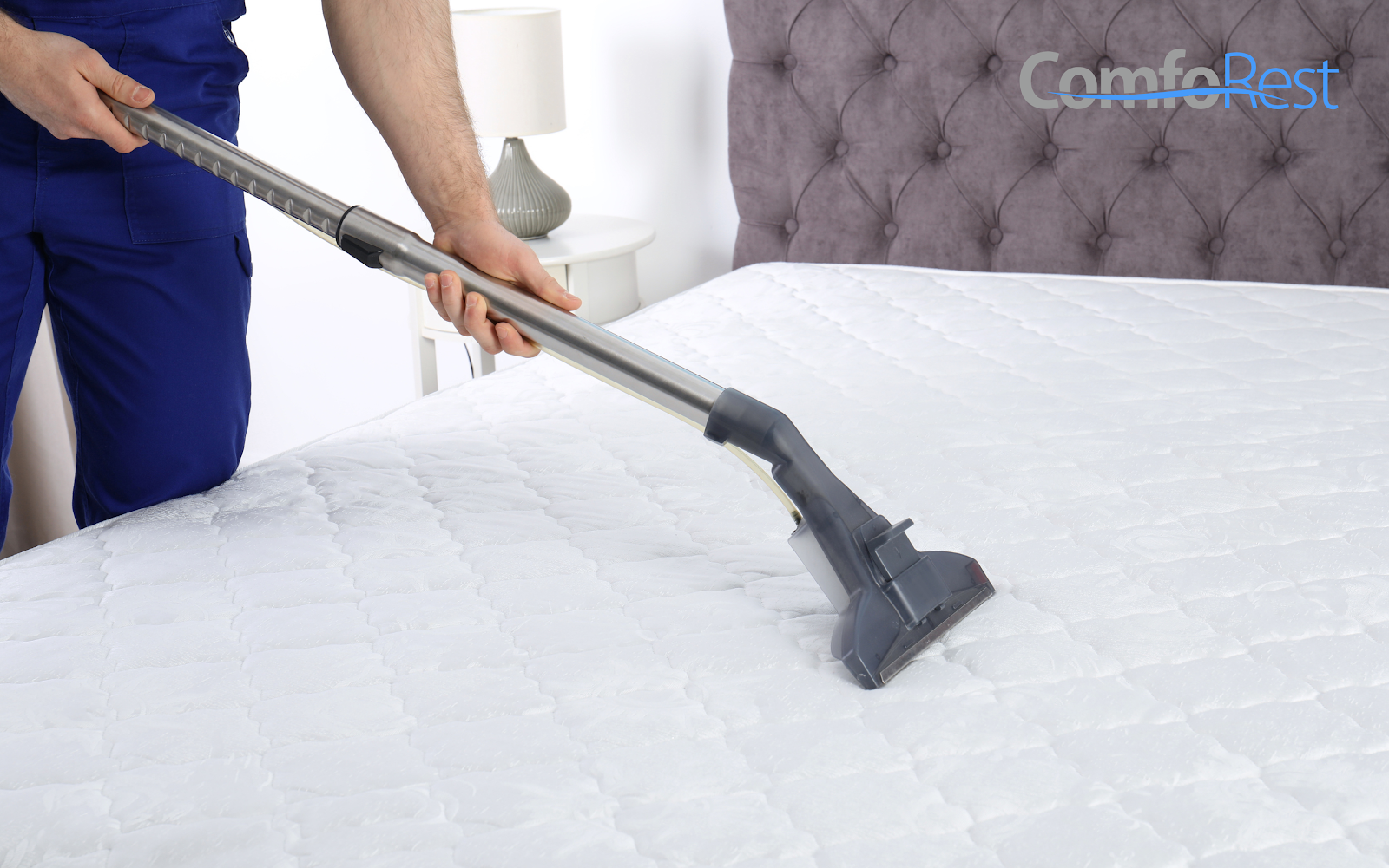 Person vacuuming a white mattress for cleaning and maintenance.