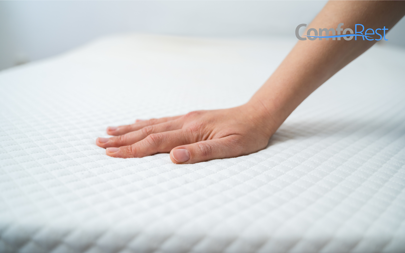 Hand pressing down on a white memory foam mattress to demonstrate pressure relief and responsiveness – ComfoRest mattress comfort test