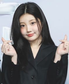 A picture of wonhee wearing a black dressing and she is making a heart sign 