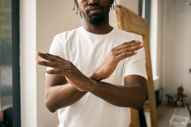 A man with dreadlocks gestures expressively with his hands showing to stop