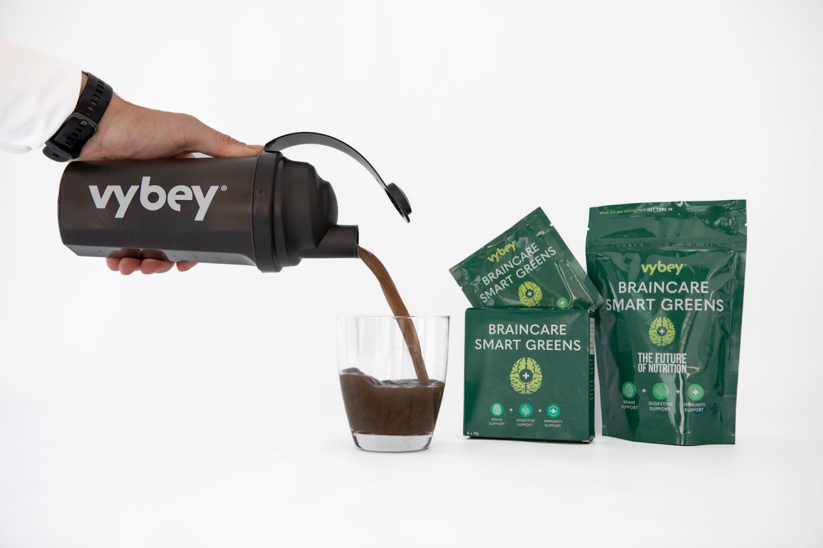 A hand pouring vybey Braincare Smart Greens powder, a nutrient-rich super greens blend designed for brain health and immunity support