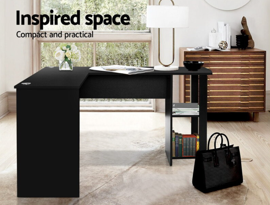 A compact and practical piece of home furniture featuring a sleek black desk with clean lines, suitable for a modern workspace. The desk includes built-in shelving for storage, and it's set against a large window, with decorative items like a vase of flowers and books enhancing the minimalist aesthetic.