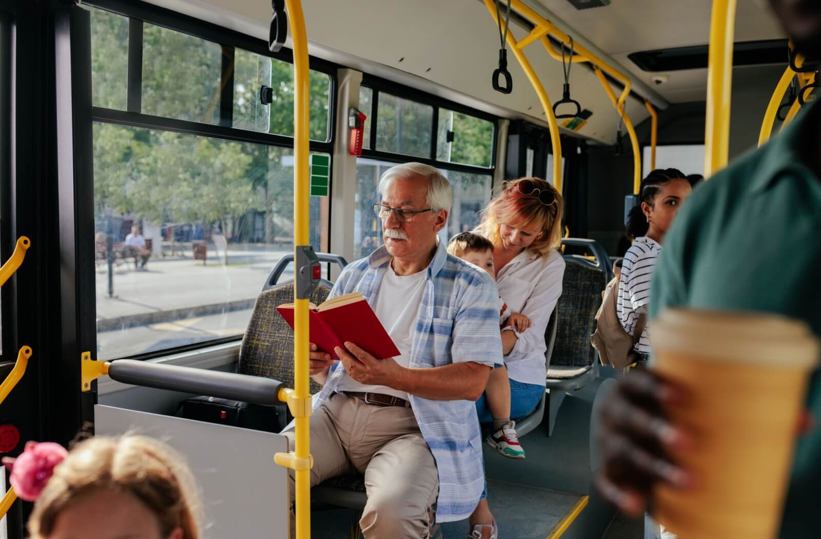 A senior enjoys reading a book while they get around independently on public transportation.