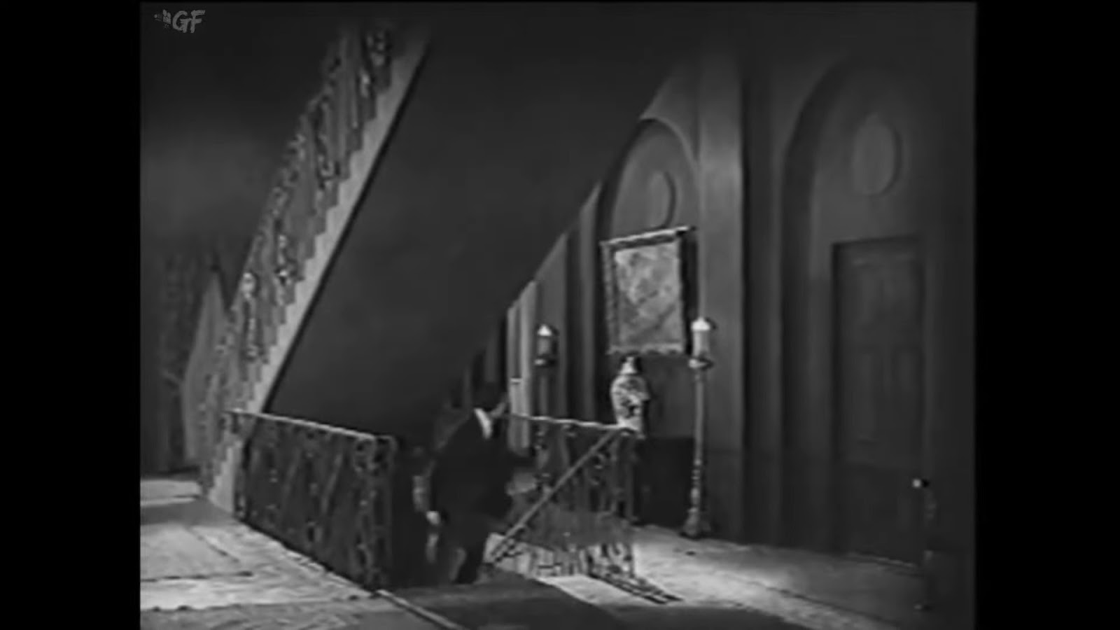 A man runs up a flight of stairs in a dark house. 