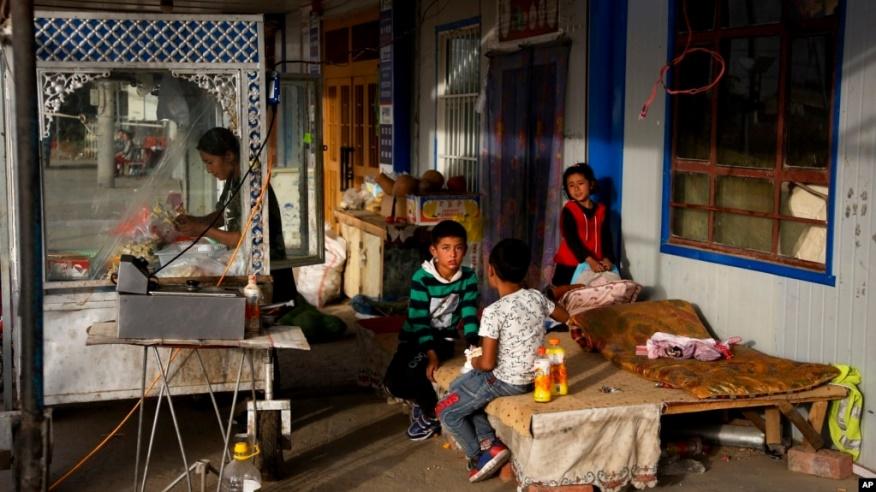 FILE - A Uyghur woman works while her children play in Hotan, in western China's Xinjiang region, Sept 20, 2018. U.S. trade figures show that as of October 2024, Southeast Asia is being hit hardest by U.S. trade restrictions on exports believed to come from Uyghur forced labor.