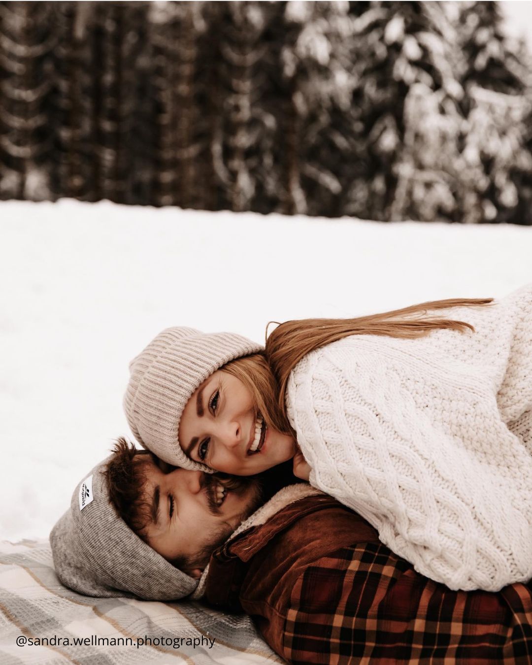 winter engagement photos a couple lying in the snow