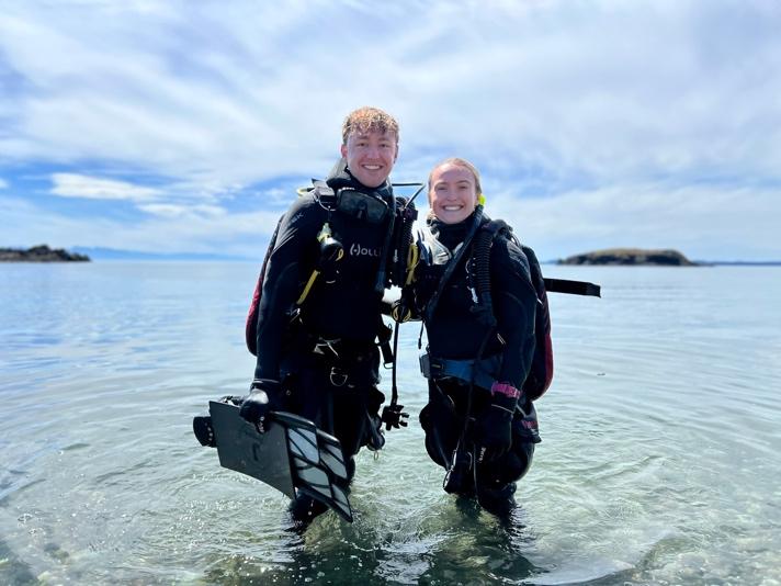 A person and person in scuba gear standing in water

Description automatically generated