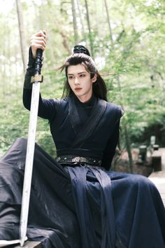 A picture of PENTAGON Yanan on a black outfit holding a sword 