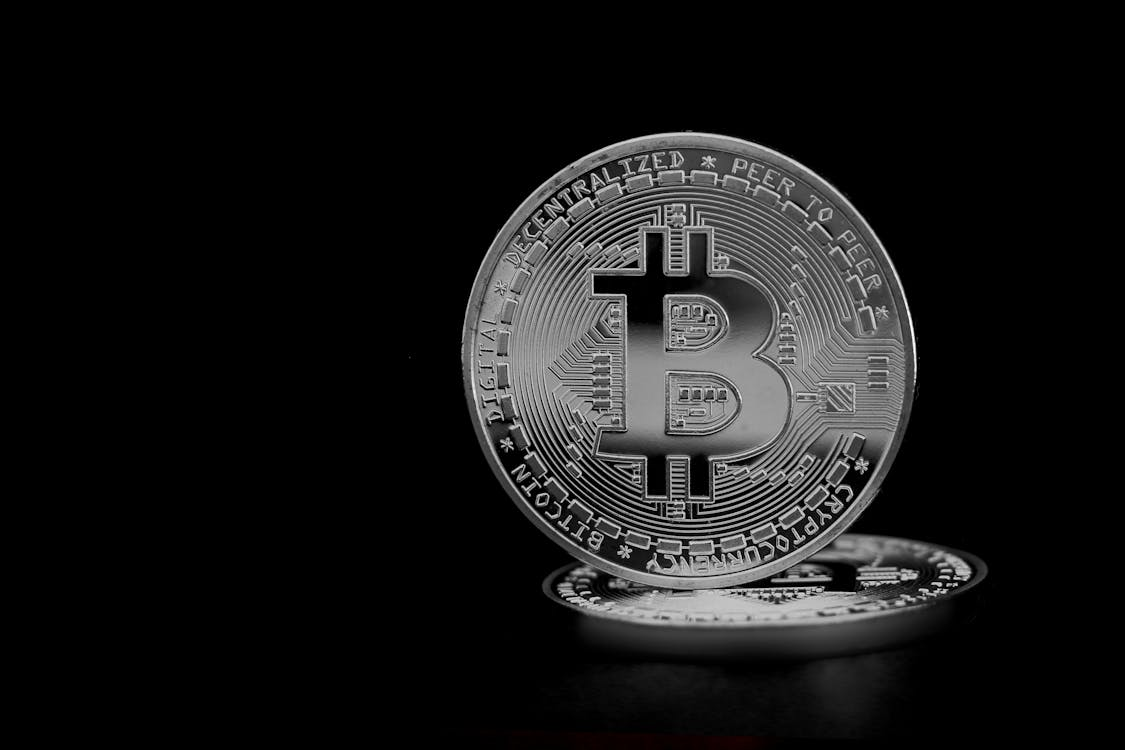 Silver Bitcoin coin reflecting on black surface representing cryptocurrency value and market trends