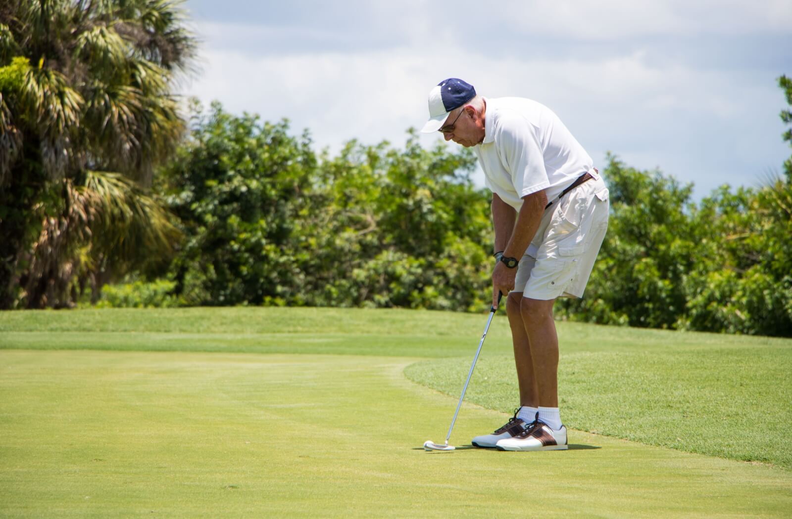 An older adult putting a golf ball.