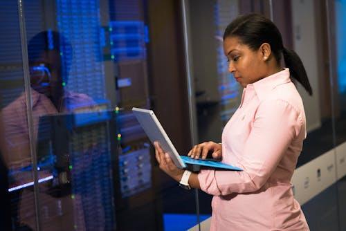 Free A focused software engineer working on a laptop in a server room, reflecting dedication in tech. Stock Photo