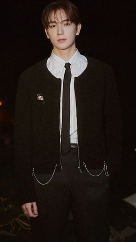 This  contain  kim hyunjae wearing a black suit and white shirt is standing in the dark with his hands in his pockets