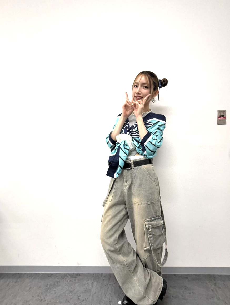 A picture of former Morning Musume star Goto Maki making the peace sign resting against the wall  