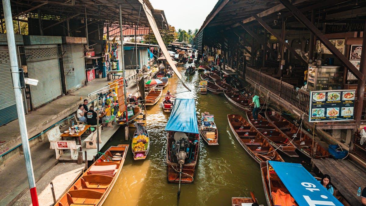 Boats in a canal with boats and people in the background

Description automatically generated