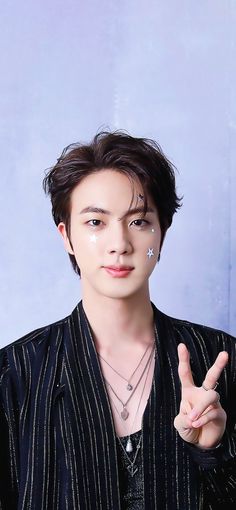 A picture of BST Jin on a black shirt making the peace sign 