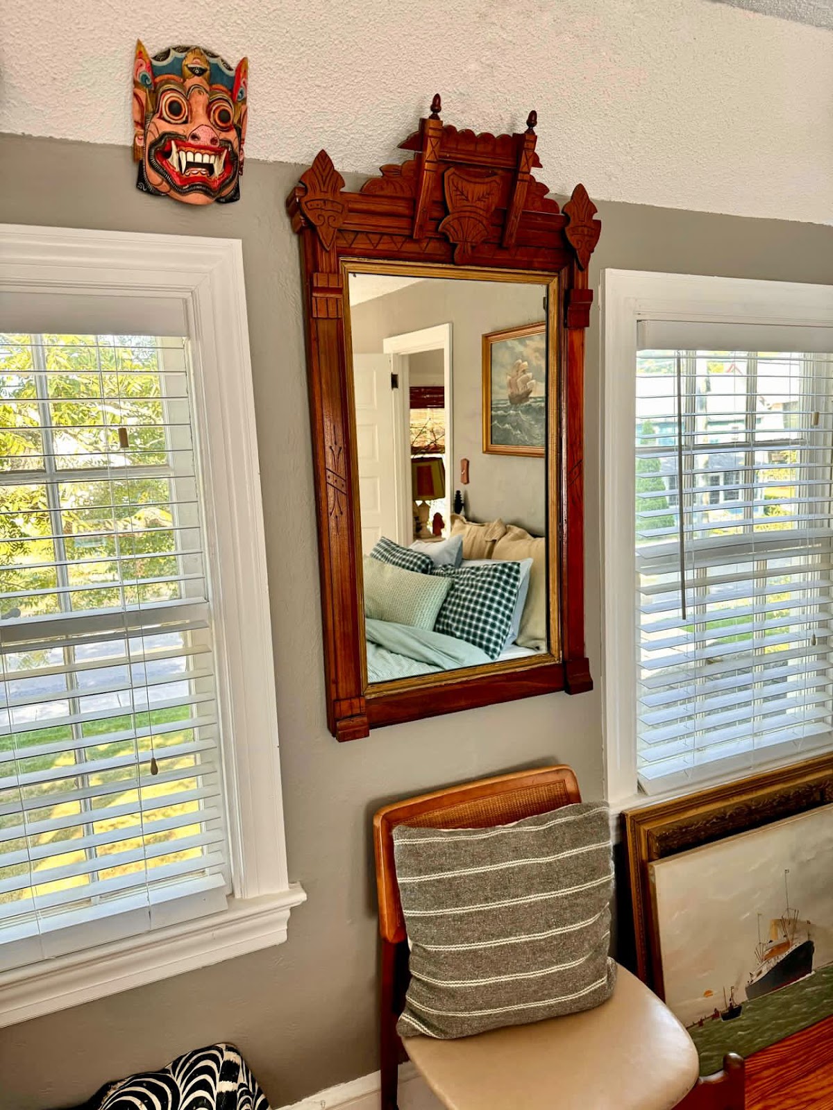 An Eastlake mirror hung on the wall in Memo's guest room between two windows reflecting the room's bed and the shipping painting hung above the bed.