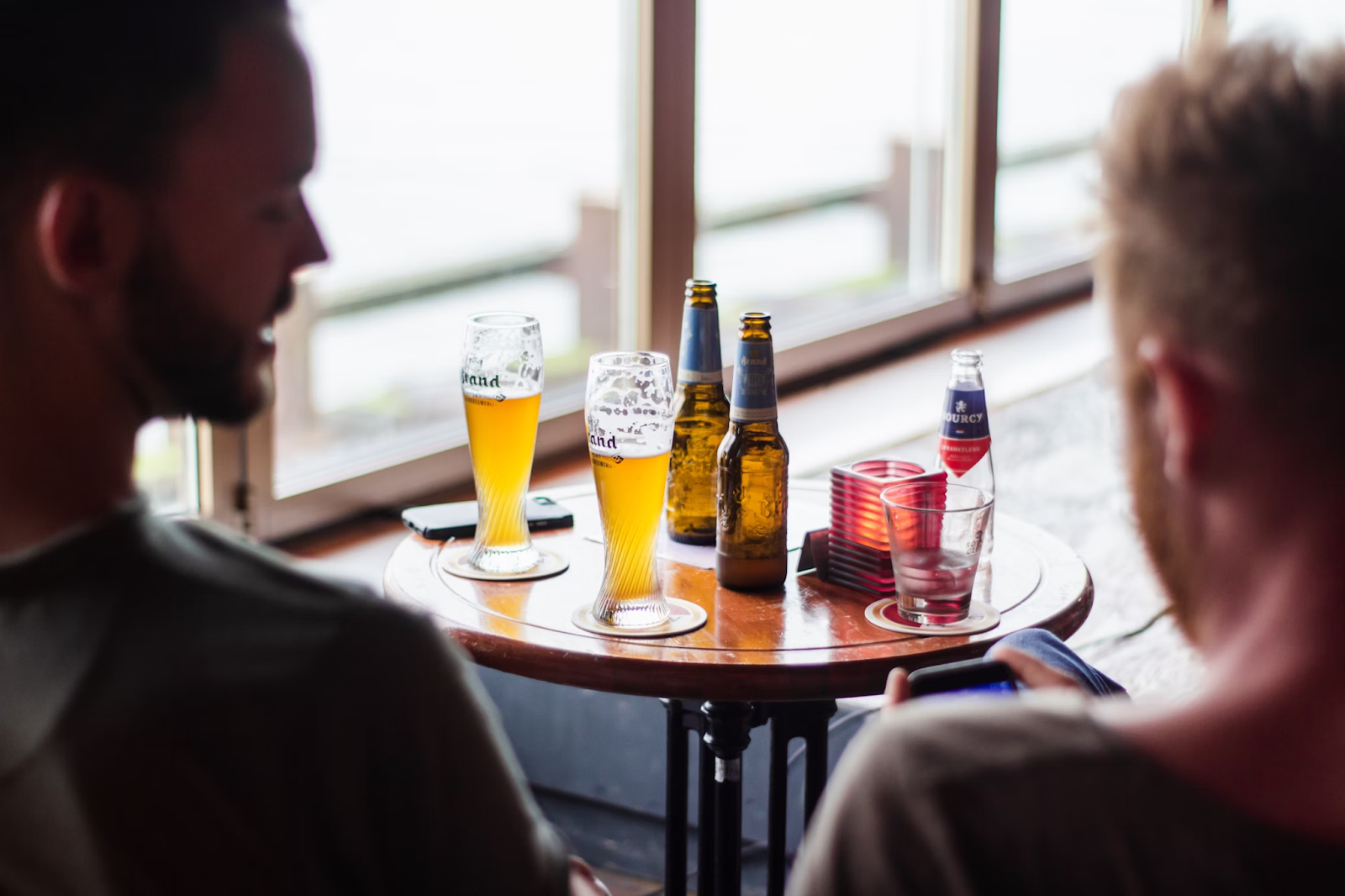 Two men sitting at a table drinking beer.