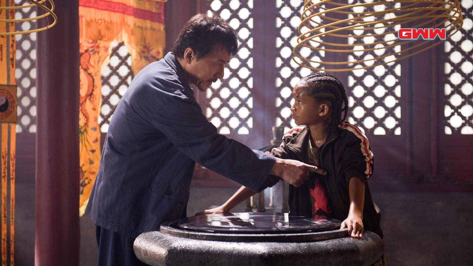 Mr. Han instructing the boy on a martial arts technique indoors.