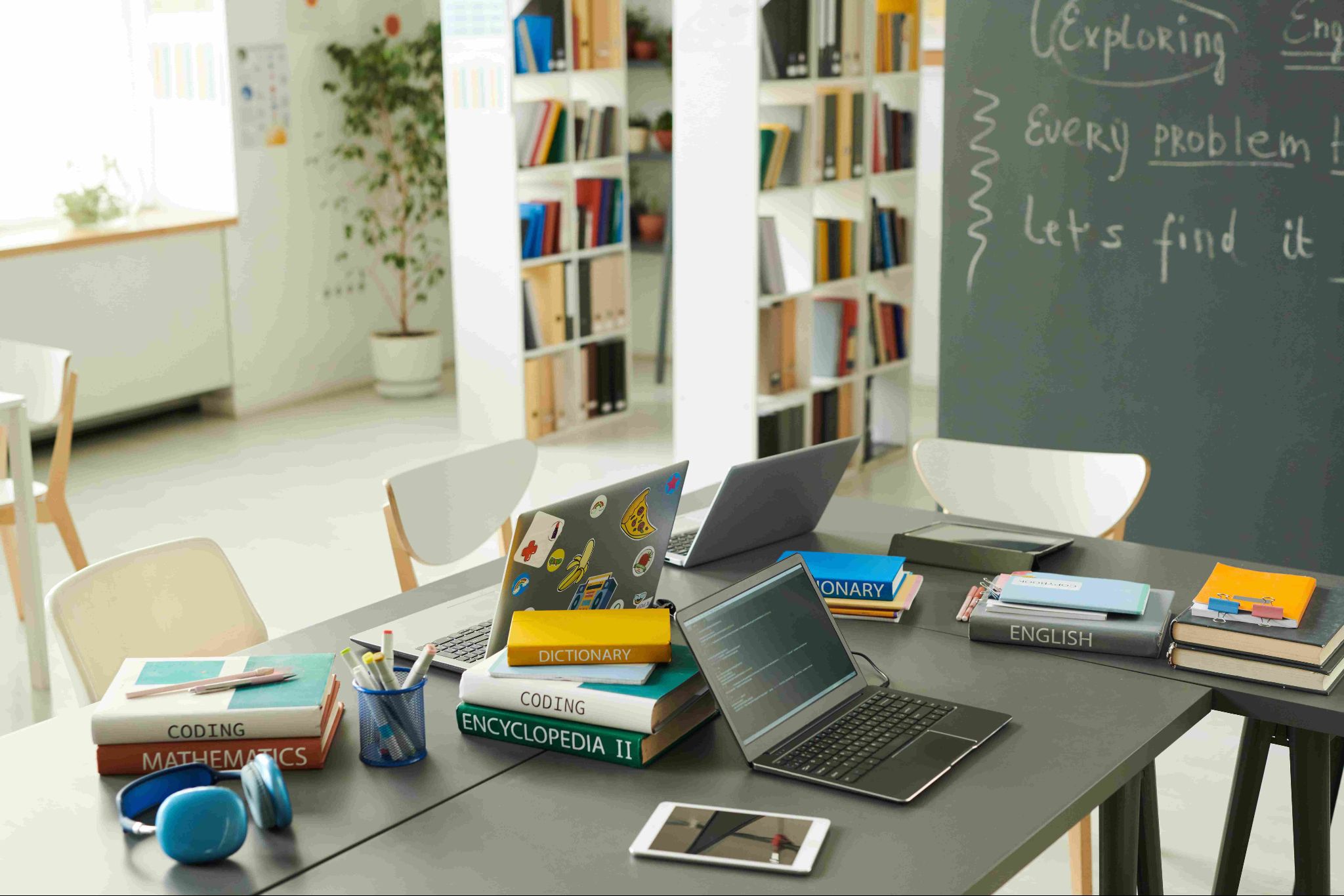 A study table with laptops, books, and stationery