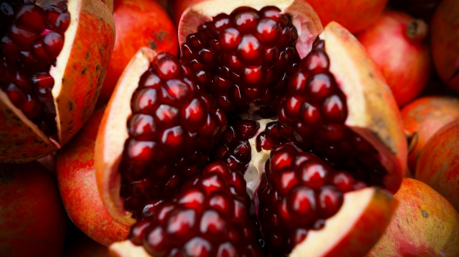 Close-up of a freshly opened pomegranate revealing its glossy, ruby-red seeds, showcasing the vibrant fruit rich in nutrients, ideal for an ADHD-friendly smoothie.