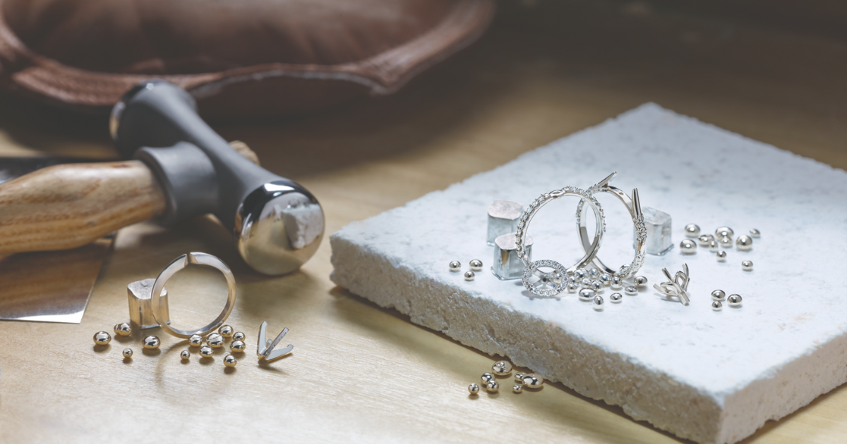 A small jeweler's hammer and white gold rings and white gold material for jewelry repair