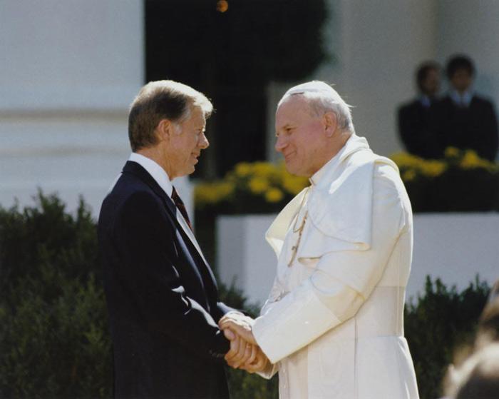 A person in a white robe shaking hands with a person in a white robe

Description automatically generated