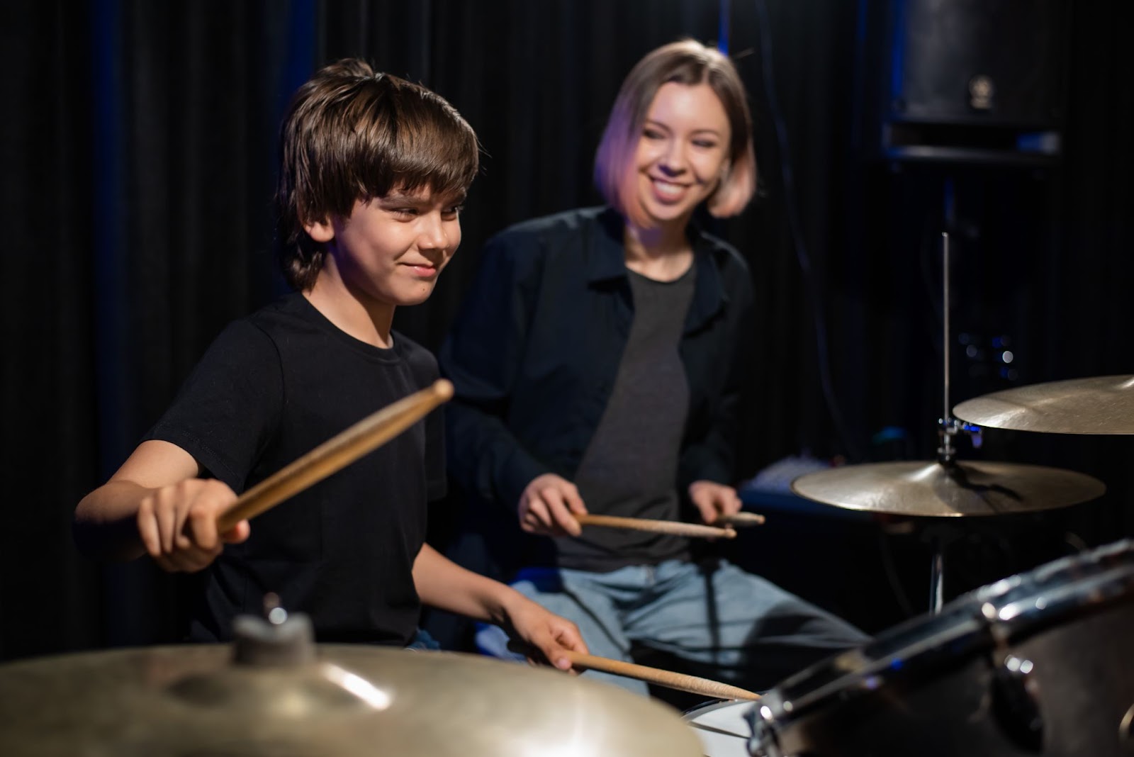 Drum teacher helping young student during a beginner lesson in London