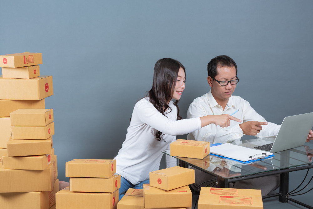 Two people are packing orders with stacks of boxes, representing e-commerce in China.