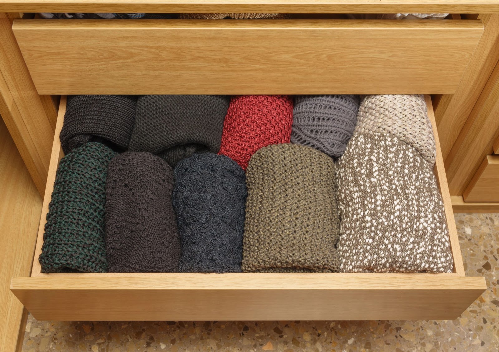 Rolled sweaters neatly arranged in a drawer for quick access