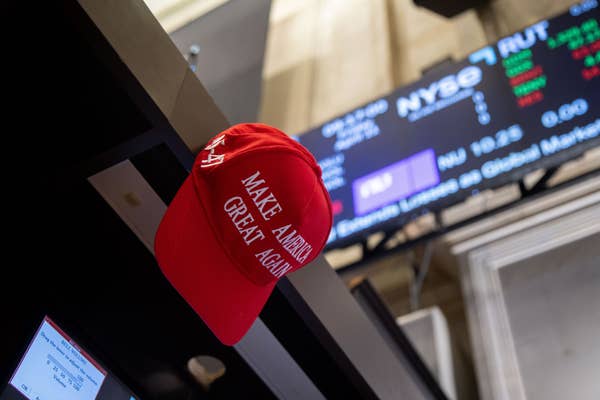 Red &quot;Make America Great Again&quot; hat on display inside a stock exchange, with electronic stock board showing numbers in the background