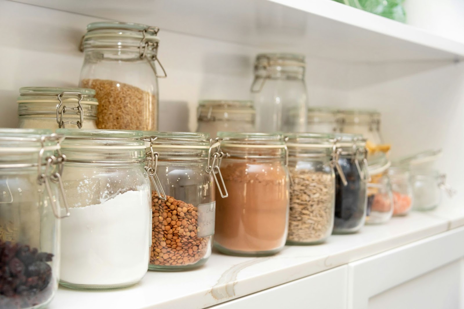 A neatly organized pantry with labeled airtight containers holding baking ingredients like flour, sugar, and oats, arranged to maximize freshness and reduce waste.