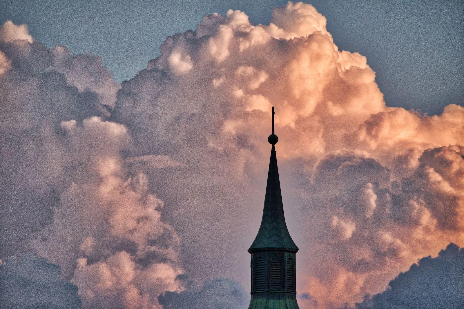 a cloudy sky and a dark steeple