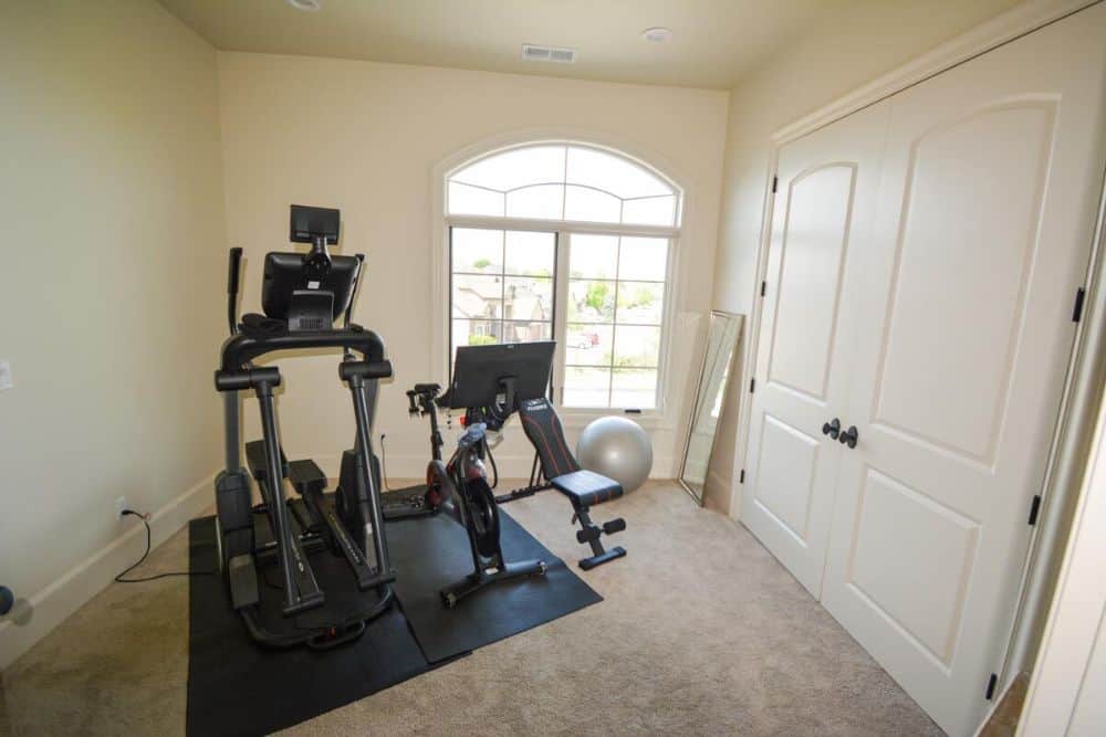 Home gym with carpet flooring, arched window, and walk-in closet concealed behind the french door.