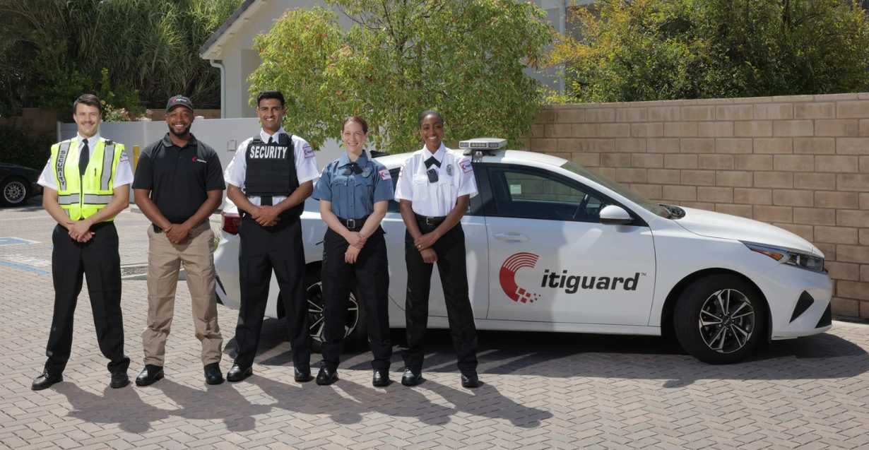 (Five Citiguard security professionals stand in uniform beside a patrol car in a sunny outdoor lot.)