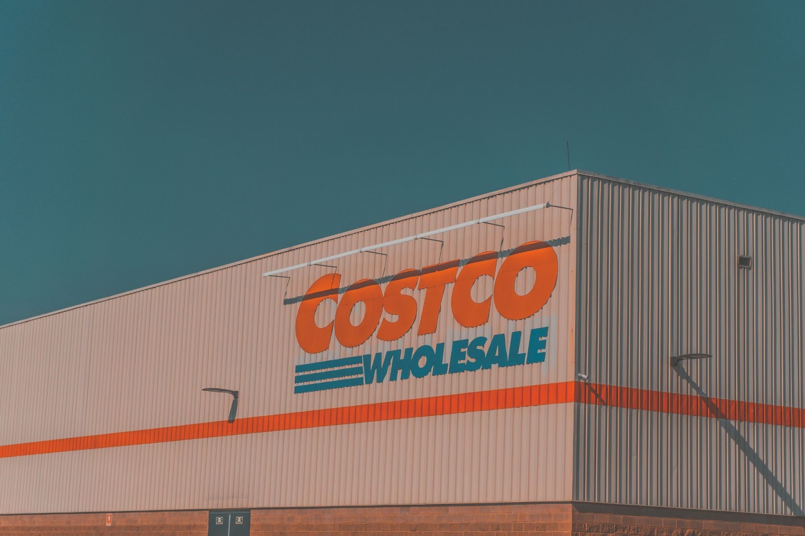 Exterior view of a Costco Wholesale building with bold orange and blue signage against a clear sky.