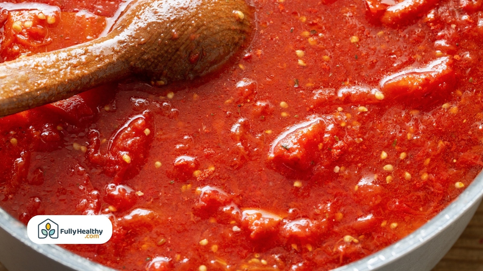 Close-up of chunky tomato sauce being stirred with a wooden spoon