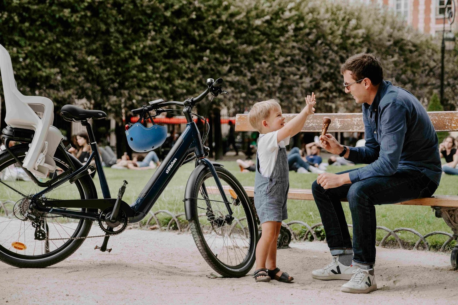 Un papa et son enfant qui se promènent dans Paris avec un vélo électrique de location doté d’un porte enfant