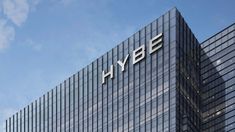 This contains an image of hybe logo on top of an office building