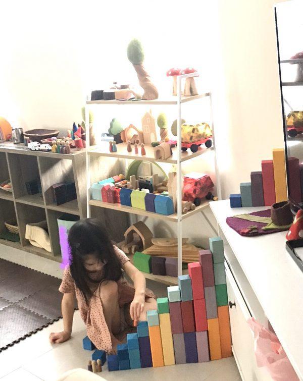 A preschooler carefully stacking blocks, focusing on proportionality and units. Here the child is honing her number skills like proportion and units. 