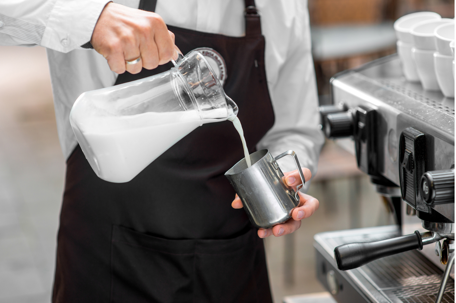 A picture of a barista pouring milk into a pitcher 