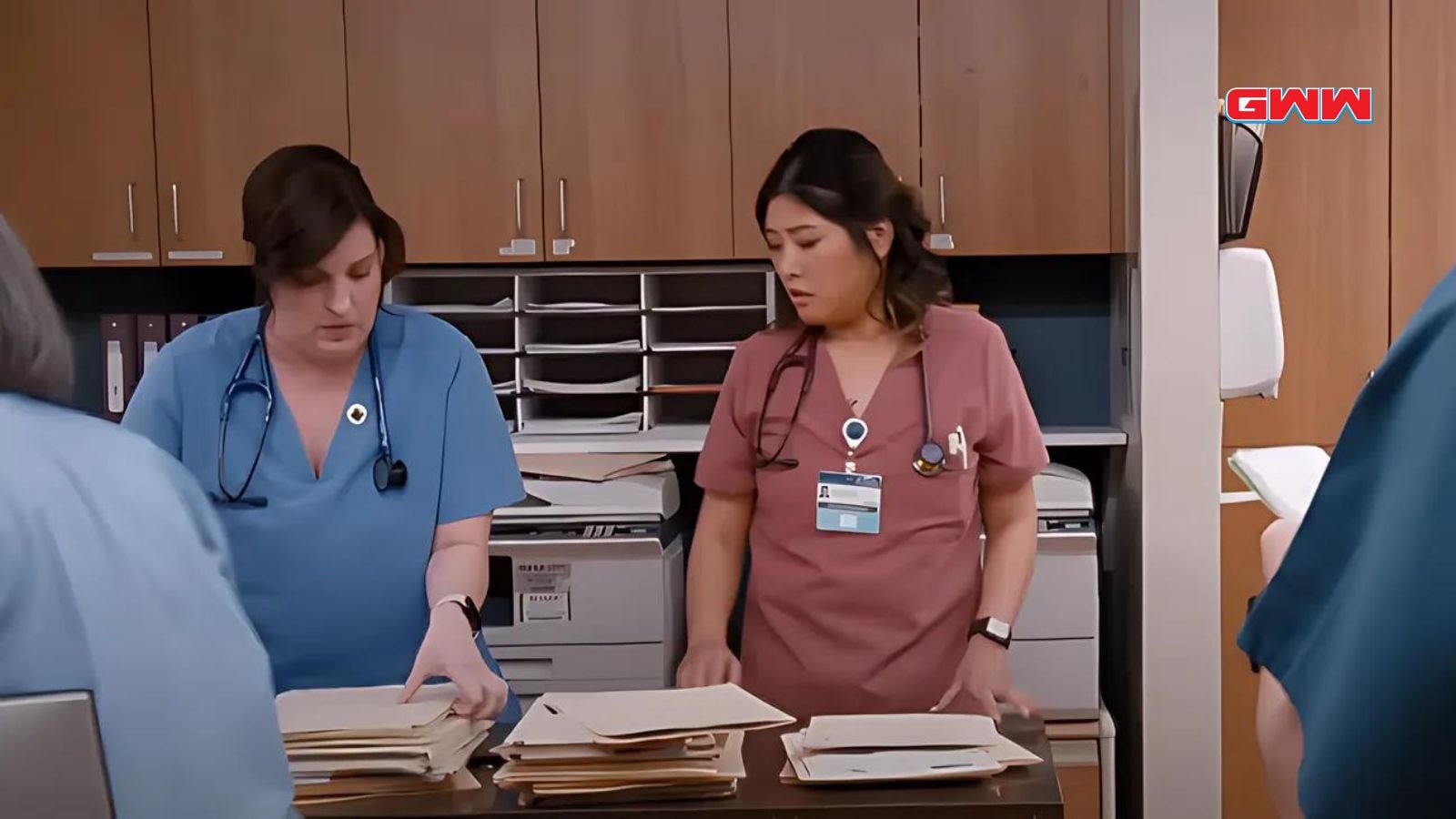 Nurses discuss paperwork in hospital, featuring Wendi McLendon-Covey