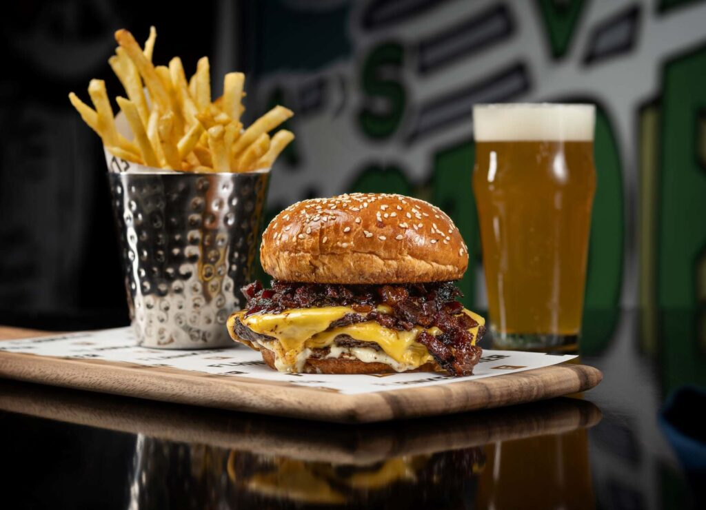 Flanker Kitchen + Sports Bar's Wagyu double-smash burger with a side of fries and a glass of beer. 