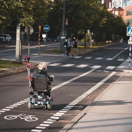 A senior riding  a mobility scooter on the sidewalk