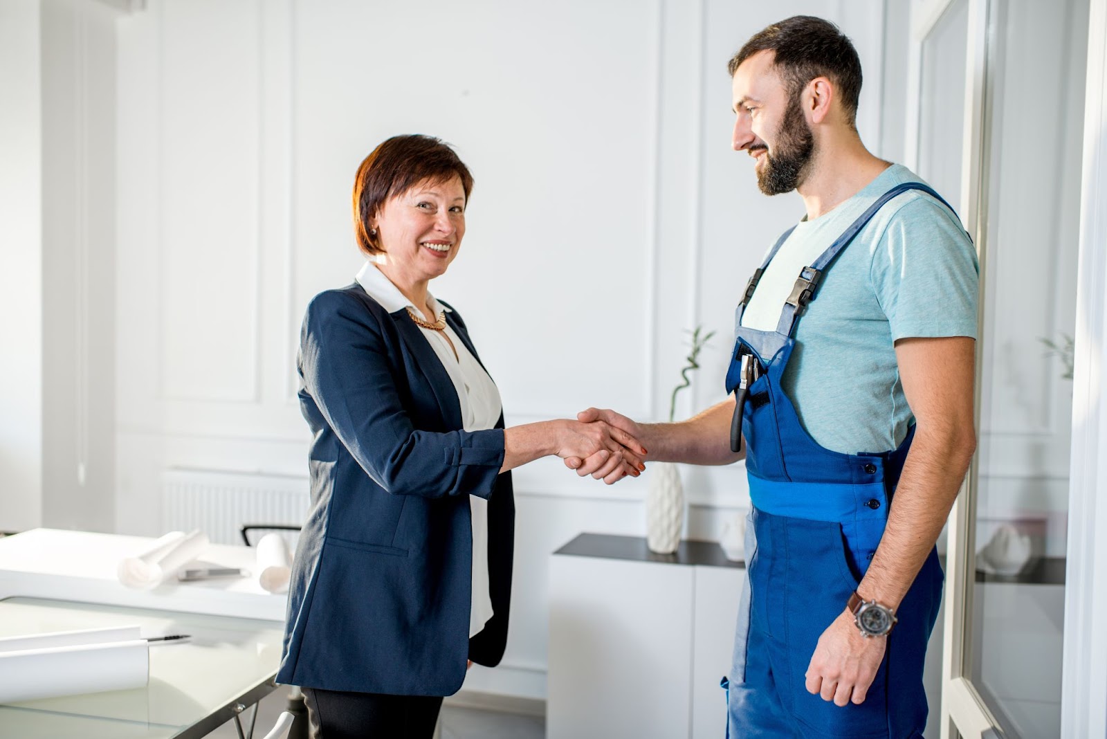 Woman shaking hands with a plumber. 