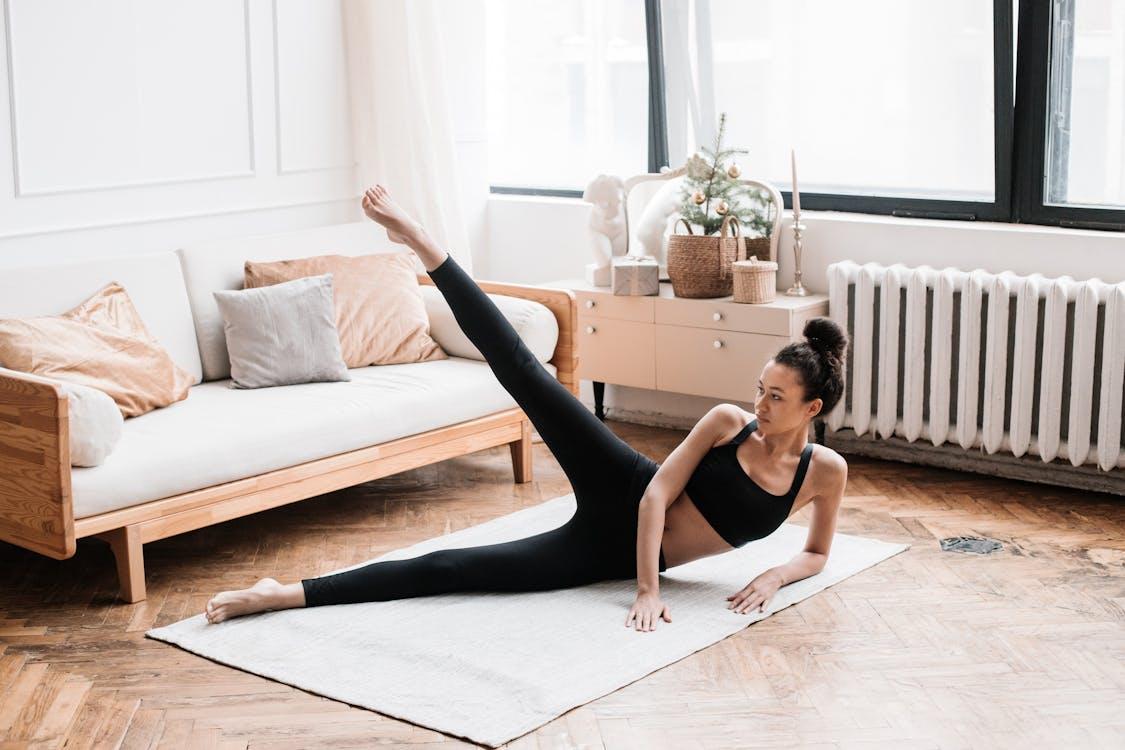 Free A woman exercises, performing yoga in a stylish living room with soft natural lighting. Stock Photo