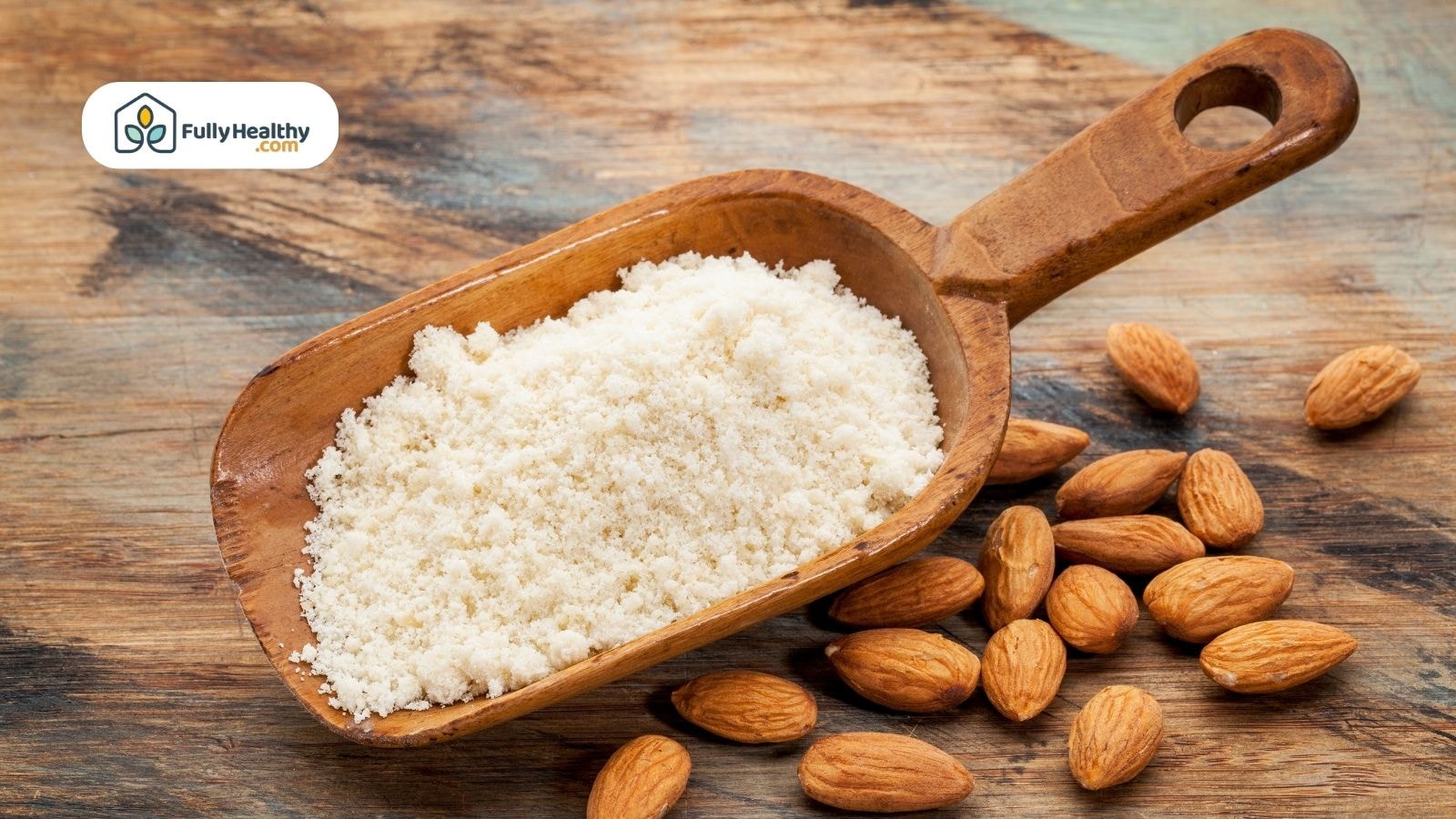 Wooden scoop filled with almond flour and almonds on rustic surface