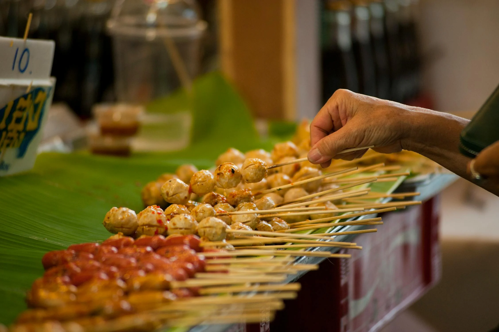 A hand holding a skewer of meatballs

Description automatically generated