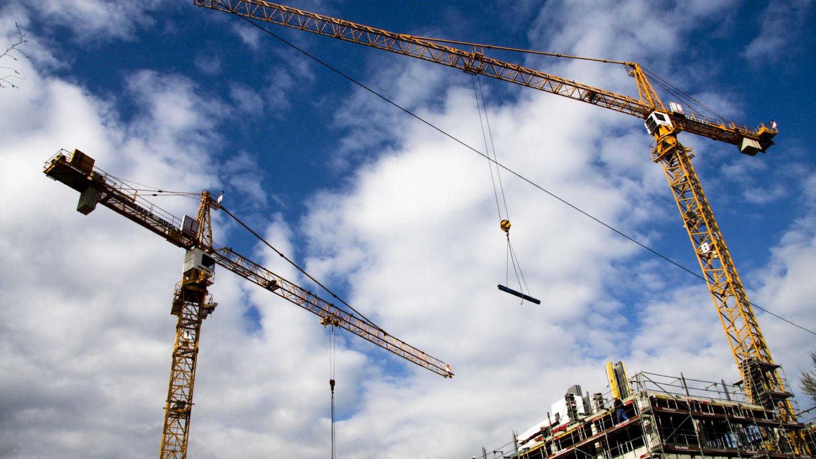 Two large cranes standing in front of a construction site